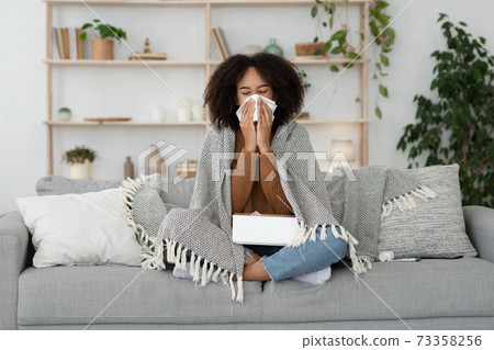 Sick day at home, treated, unhealthy african american millennial woman has runny nose, cough and common cold 73358256