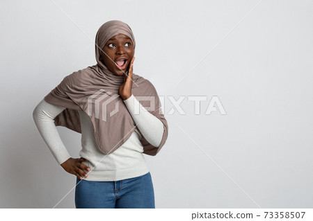 Shocking Offer. Surprised black islamic lady in hijab touching face in excitement Shocking Offer. Surprised black islamic lady in hijab touching face in excitement 73358507