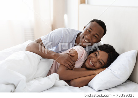 Romantic black couple bonding in bed at home 73359325