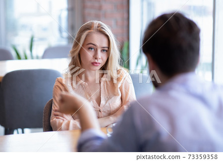 Bad date. Young woman feeling bored during dinner at cafe, unhappy with her boyfriend, disinterested in conversation Bad date. Young woman feeling bored during dinner at cafe, unhappy with her boyfriend, disinterested in conversation 73359358
