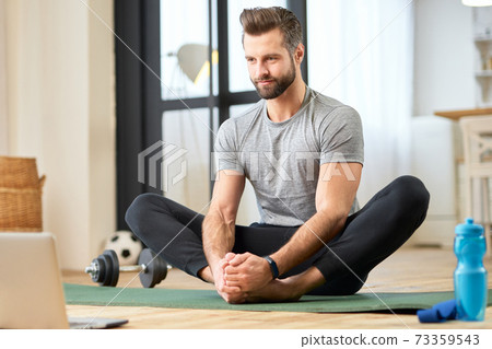 Handsome young man using laptop and working out at home Handsome young man using laptop and working out at home 73359543