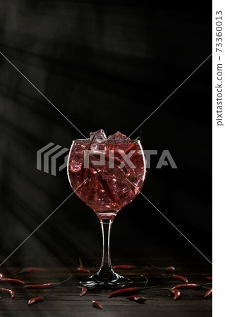 Red cocktail in a glass with ice and chili peppers. Valentine's Day Concept Red cocktail in a glass with ice and chili peppers. Valentine's Day Concept 73360013