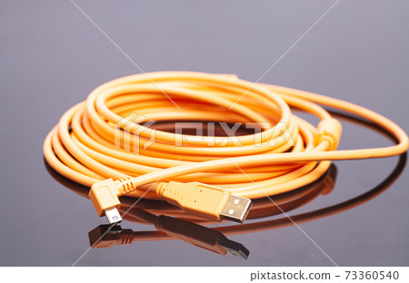 Orange rolled cable on black background Orange rolled cable on black background 73360540