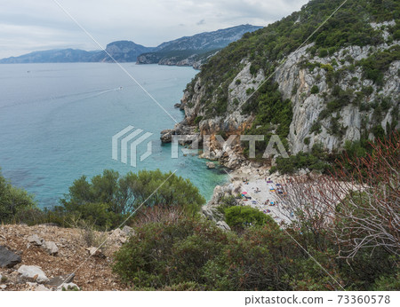 Aerial view of Cala Fuili beach near Cala Gonone, Gulf of Orosei, Sardinia island, Italy. White pebbles beach with limestone rocks and turquoise blue water. Famous travel touristic destination Aerial view of Cala Fuili beach near Cala Gonone, Gulf of Orosei, Sardinia island, Italy. White pebbles beach with limestone rocks and turquoise blue water. Famous travel touristic destination 73360578