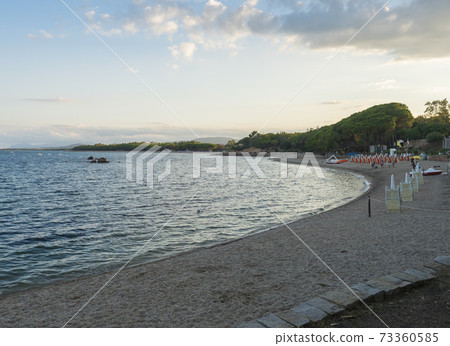 view of sand beach Spiaggia di Santa Maria Navarrese, sea with green forest and view of Arbatax penisula. Golden hour light, Sardinia, Italy 73360585