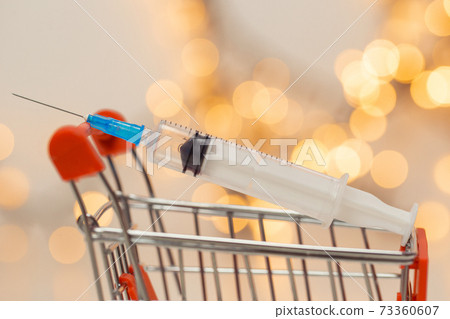 syringe injection in shopping cart for coronavirus vaccine disease, covid-19 or other virus, vaccination shot, medicine and drug concept bokeh background 73360607