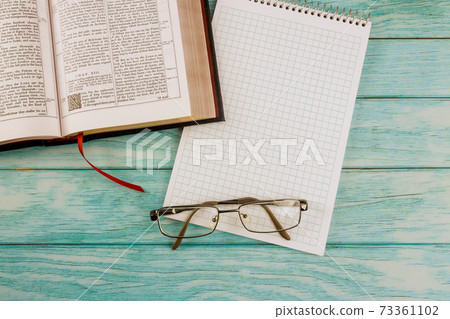 Opened the Holy Bible close up prayer time in eyeglasses on notepad 73361102