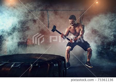 Sports training for endurance, man hits hammer. Concept workout Sports training for endurance, man hits hammer. Concept workout 73361136