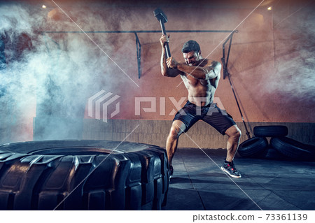 Sports training for endurance, man hits hammer. Concept workout Sports training for endurance, man hits hammer. Concept workout 73361139