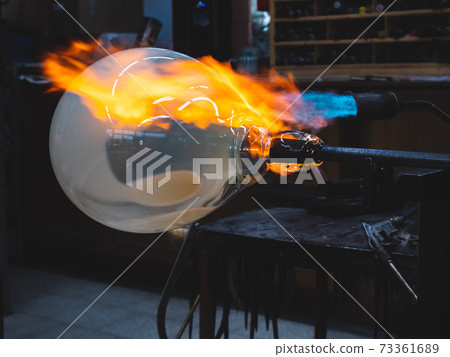 Creating traditional glass Art with Hot Torch and glassblowing pipe. 73361689