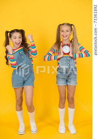 two happy girls hold alarm clock. back to school. two happy girls hold alarm clock. back to school. 73361892