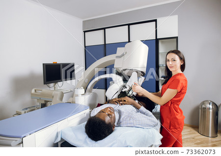 Treatment of urethral stones by non-invasive Extracorporeal Shock Wave Lithotripsy. Pleasant female doctor providing the ultrasonic lithotripsy for her male African patient in modern clinic Treatment of urethral stones by non-invasive Extracorporeal Shock Wave Lithotripsy. Pleasant female doctor providing the ultrasonic lithotripsy for her male African patient in modern clinic 73362073