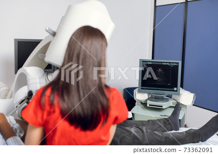 Extracorporeal Shockwave Therapy in Urology. Back view of female doctor working with modern ultrasonic lithotripter to crush kidney stones. Focus on the digital screen with ultrasound image Extracorporeal Shockwave Therapy in Urology. Back view of female doctor working with modern ultrasonic lithotripter to crush kidney stones. Focus on the digital screen with ultrasound image 73362091