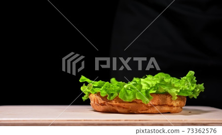 Craft burger is cooking. Consist: red sauce salsa, lettuce, red onion, pickle, cheese, chilli green pepper, air bun and marbled meat beef. 73362576