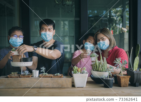 asian family wearing face mask planting cactus at home 73362641