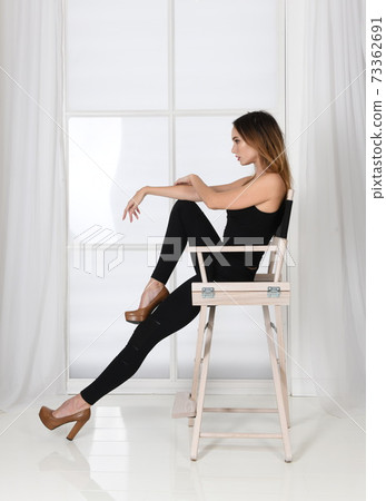 Fashion pose - woman sits on chair in model pose in high heels Fashion pose - woman sits on chair in model pose in high heels 73362691