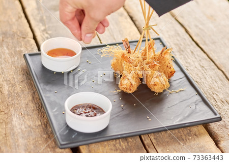Chef hand adding sesame to fried shrimps. 73363443