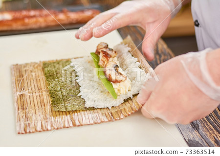 Cook hands making japanese sushi roll. 73363514