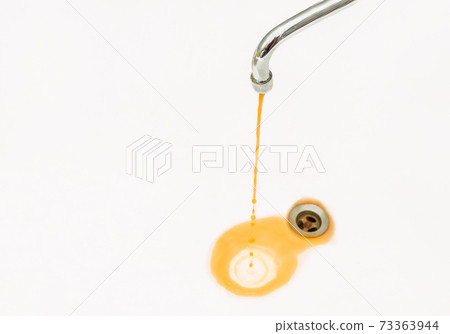 Rusty or dirty water flows from a tap into a sink or bathtub 73363944