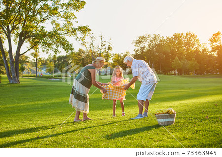 Girl with grandparents, picnic. 73363945