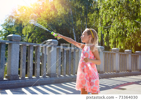 Child with bubble blower outdoors. Child with bubble blower outdoors. 73364030