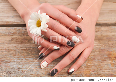 Well-groomed hands and white chrysanthemum. Well-groomed hands and white chrysanthemum. 73364132