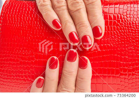 Close up red lacquered handbag in woman hands. Close up red lacquered handbag in woman hands. 73364200