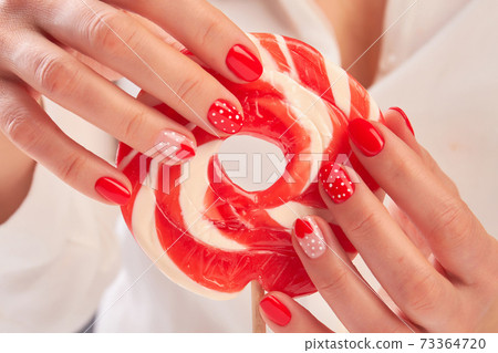 Big lollipop in manicured female hands. Big lollipop in manicured female hands. 73364720