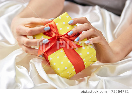 Woman manicured hands with gift box. Woman manicured hands with gift box. 73364781