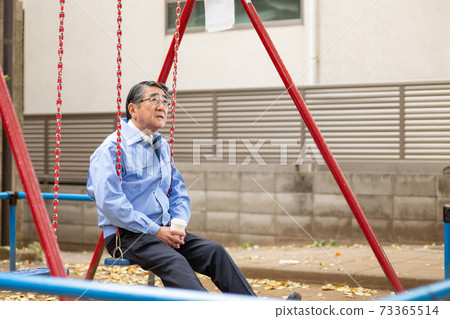 一個穿著工作服的人在公園的鞦韆上的暮光之城 一個穿著工作服的人在公園的鞦韆上的暮光之城 73365514