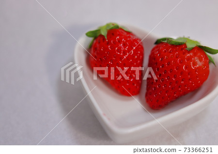 Two strawberries in a heart-shaped plate (white background) Two strawberries in a heart-shaped plate (white background) 73366251