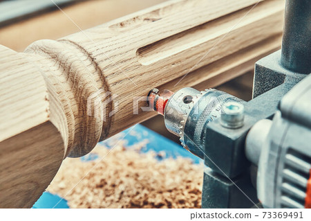 Turning wooden stair balusters. Wood stair balusters manufacturing process on a turning lathe with milling cutter Turning wooden stair balusters. Wood stair balusters manufacturing process on a turning lathe with milling cutter 73369491