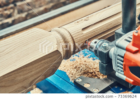 Turning wooden stair balusters. Wood stair balusters manufacturing process on a turning lathe with milling cutter 73369624