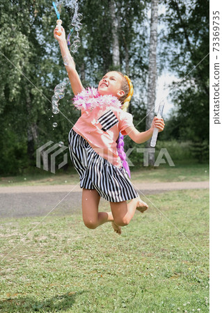little girl jumping and blowing up soap bubbles. little girl jumping and blowing up soap bubbles. 73369735