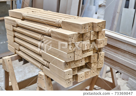 Turning wooden stair balusters. Wood stair balusters stacked in workshop Turning wooden stair balusters. Wood stair balusters stacked in workshop 73369847