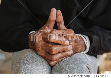 Hands of an old man on the wood table .vintage tone. Hands of an old man on the wood table .vintage tone. 73370416