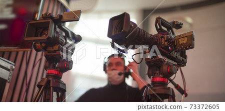 masked cameraman is filming a television show in the studio. masked cameraman is filming a television show in the studio. 73372605