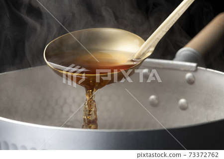 Scoop the soup stock with a ladle 73372762