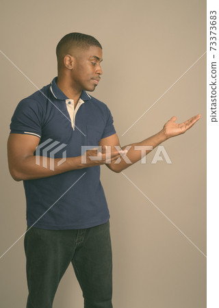 Young handsome African man wearing blue polo shirt against gray background 73373683