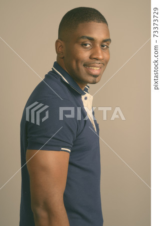 Young handsome African man wearing blue polo shirt against gray background Young handsome African man wearing blue polo shirt against gray background 73373729