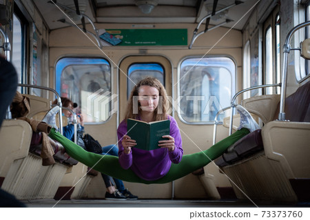 Girl sitting on the split in the subway car and reading book. Concept of education and self-development. Girl sitting on the split in the subway car and reading book. Concept of education and self-development. 73373760
