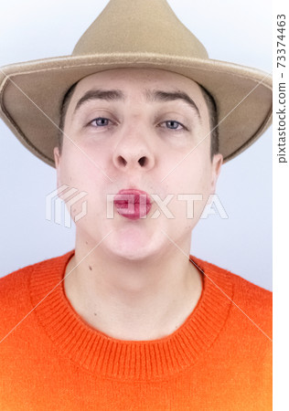 A man with painted lips, wearing women's clothing and makeup, stands in front of a mirror and admires himself. Protecting the rights of the LGBT community and openly manifesting homosexuality. 73374463