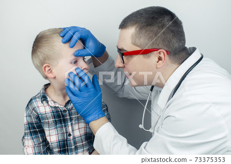 An ophthalmologist examines a boy who complains of burning and pain in his eyes. Eye fatigue from a computer or phone screen (sensation of sand on the cornea). Diagnosis of conjunctivitis in children. 73375353