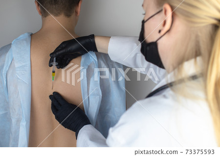 An allergist in the laboratory conducts an allergy prick-test. Skin test for household, food, epidermal allergic reactions. The test is performed on the patient back 73375593