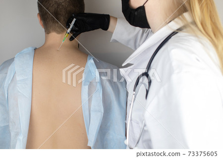 An allergist in the laboratory conducts an allergy prick-test. Skin test for household, food, epidermal allergic reactions. The test is performed on the patient back 73375605