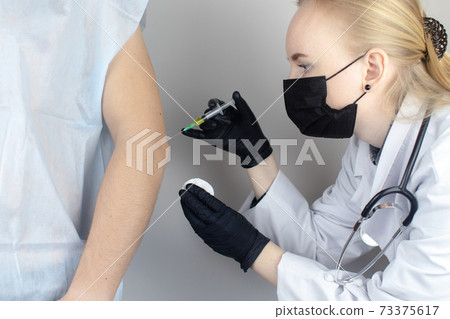 An orthopedic surgeon gives an injection in the elbow. Treatment of osteoarthritis with hormonal drugs or drugs based on hyaluronic acid. Help with diseases that damage the cartilage of the joint 73375617