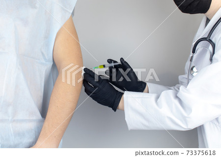 An orthopedic surgeon gives an injection in the elbow. Treatment of osteoarthritis with hormonal drugs or drugs based on hyaluronic acid. Help with diseases that damage the cartilage of the joint 73375618