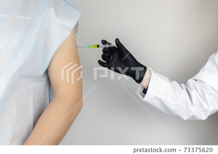 Infectious disease doctor gives the patient a medical vaccination in the shoulder. Immunization against tetanus, influenza, dysentery, whooping cough, diphtheria, measles, shigellosis and hepatitis B 73375620