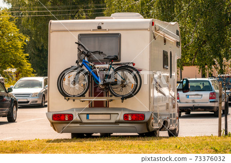Two pleasure bikes are strapped to the back of the camper van 73376032