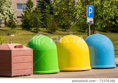 The different colored bins in the parking lot for collection of recycled materials 73376166